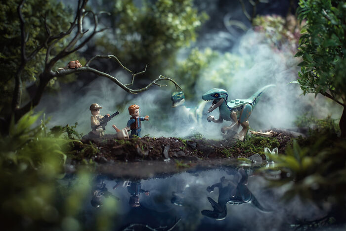 LEGO figures facing a dinosaur in a foggy forest scene created by a photographer turning LEGO into Hollywood-level scenes.