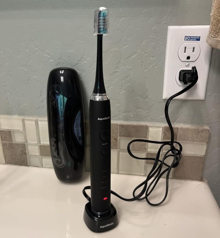 Electric toothbrush charging on a bathroom counter with AquaSonic brand, featured in Prime Day deals.