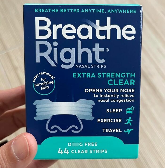 Breathe Right nasal strips box held in hand, extra strength clear strips to fix nasal congestion glitches.