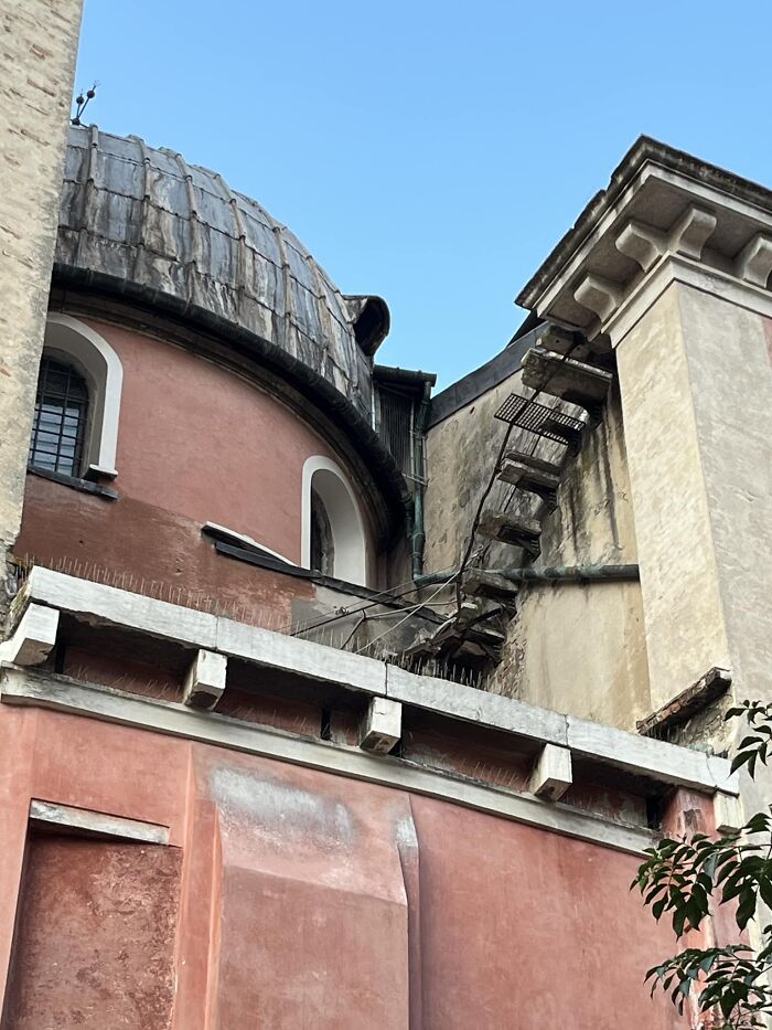 Rusty and broken death stairs attached high on an old building showing a dangerous and narrow climb outdoors.