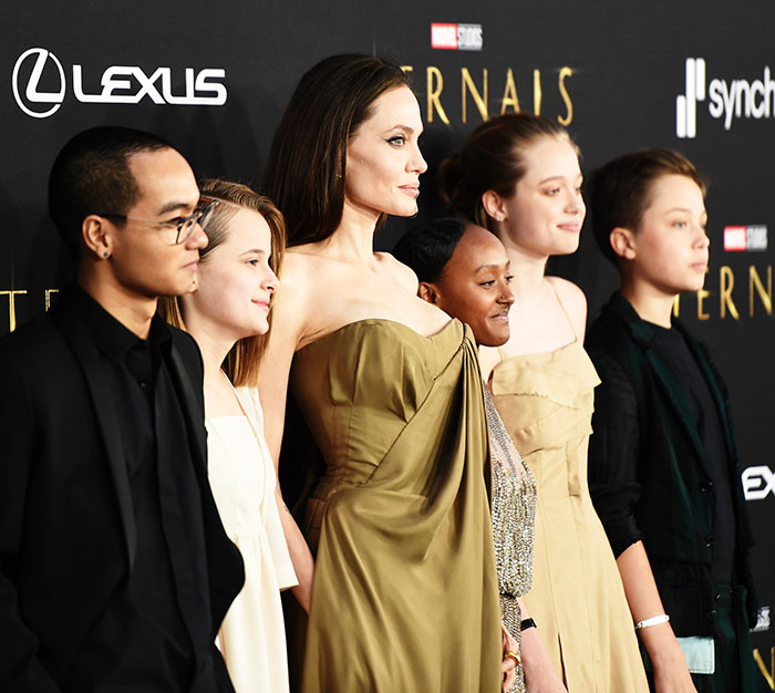 Angelina Jolie with her children posing at a red carpet event amid Brad Pitt family contact rumors.