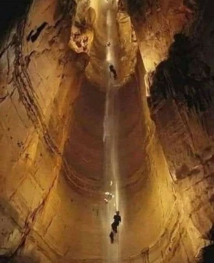 Explorers descending into a deep archaeological underground cave, showcasing historical excavation and exploration efforts.