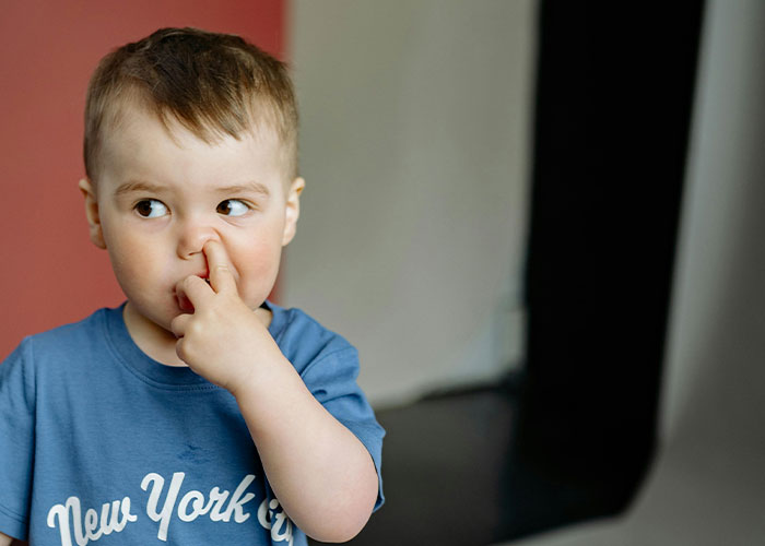 Young child in a blue shirt picking nose, illustrating reactions from buffet workers to their wildest encounters and experiences.
