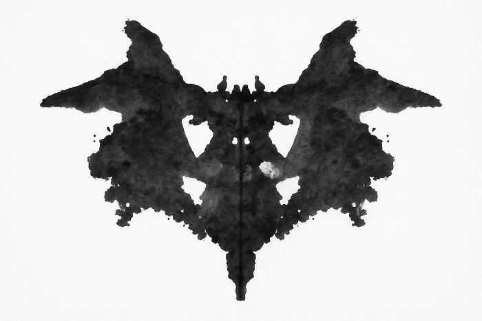 Symmetrical black Rorschach inkblot on white background, used for psychological testing and personality analysis polls.
