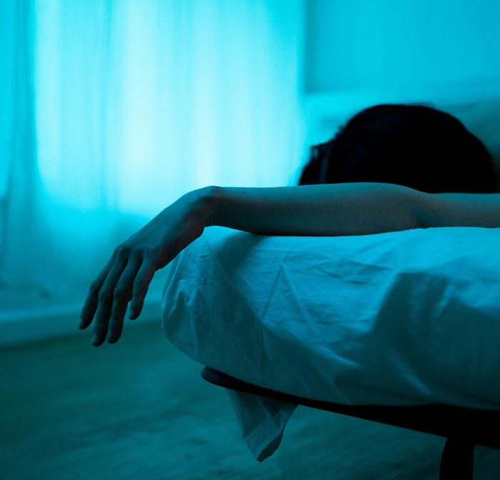 Person lying on bed with arm hanging off edge, conveying emotions related to therapy and mental health revelations.