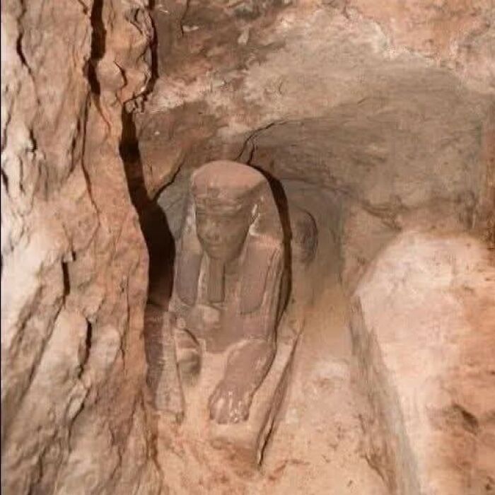 Ancient Egyptian statue partially uncovered in an archaeology world excavation site revealing historical artifacts.