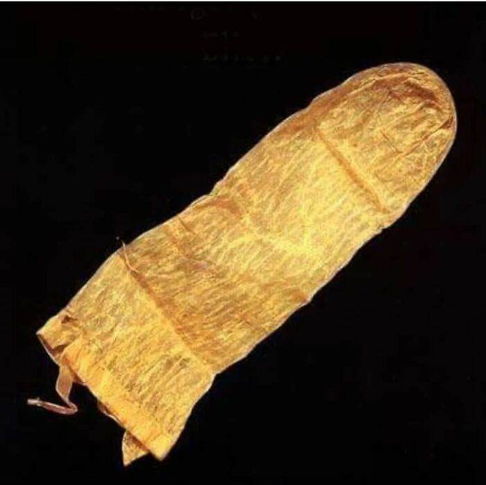 Ancient golden burial shroud shaped like a foot, displayed against a black background in archaeology world.