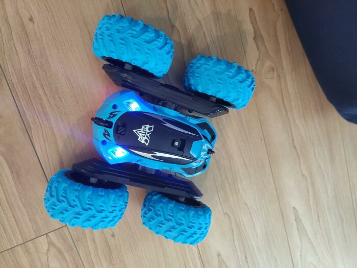 Blue remote control toy car with large tires on wooden floor, illustrating shopping for a 12-year-old gift ideas.