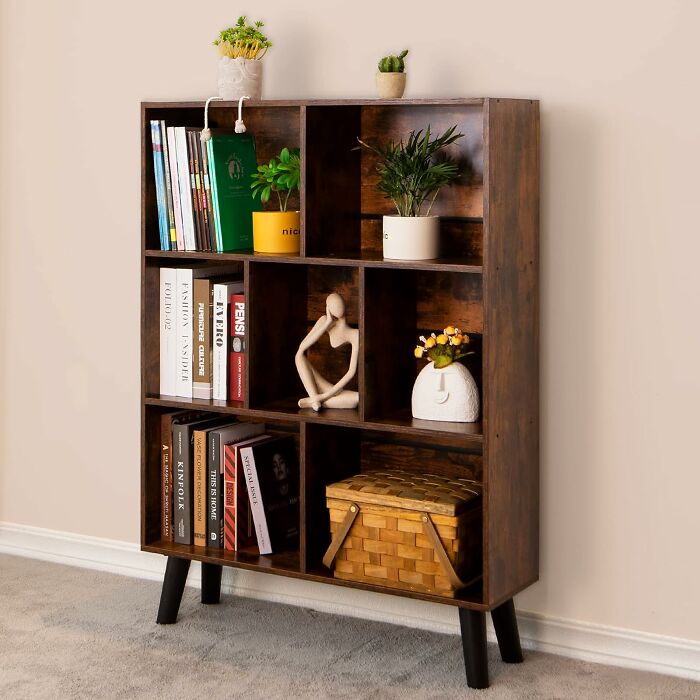 Wooden bookshelf with multiple compartments filled with books, plants, and decorative items for Prime Day home deals.