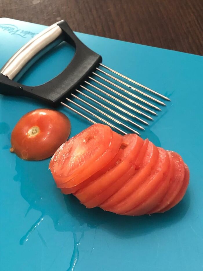 Tomato sliced evenly using a specialized food tool from unique products for problems so specific you'll swear someone is spying on you.