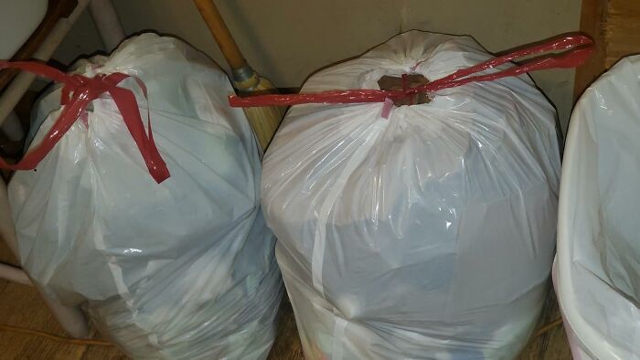 Two large trash bags tied with red plastic strips in a corner, illustrating saving money on Prime Day deals.