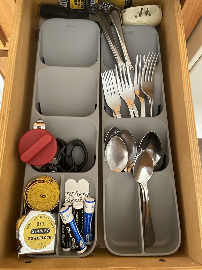 Organized drawer with updated utensil tray holding forks, spoons, tape measure, scissors, and chapsticks showcasing invention glow up.
