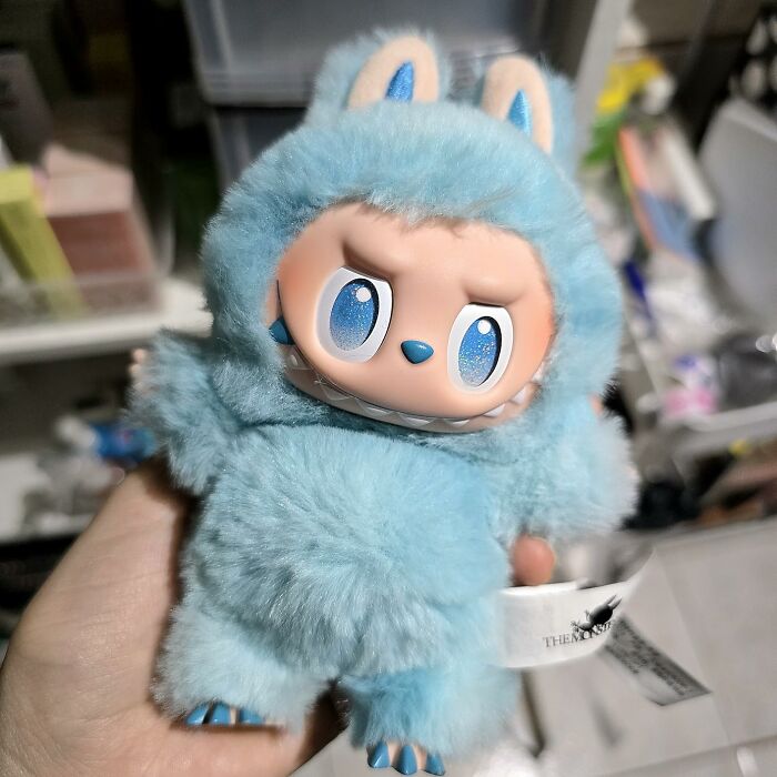 Blue plush toy with big eyes held in hand, representing shopping for a 12-year-old gift idea.