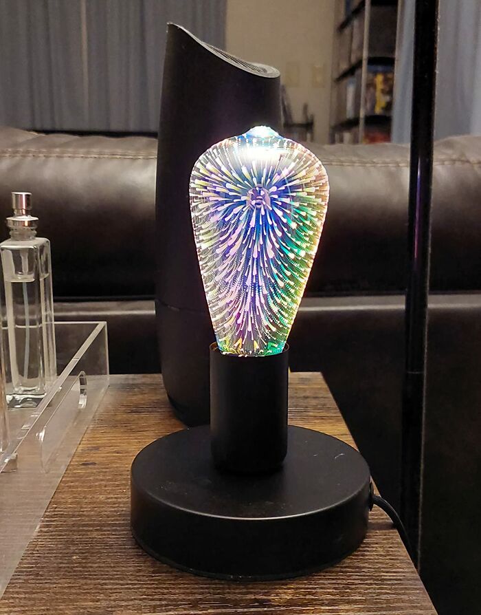 Decorative light bulb with colorful 3D firework effect on black base, enhancing outdoor space lighting usability after dark.