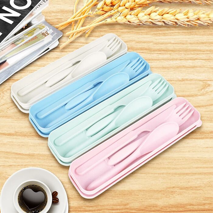 Reusable portable cutlery sets in various pastel colors arranged on a wooden surface for an al fresco picnic feast.