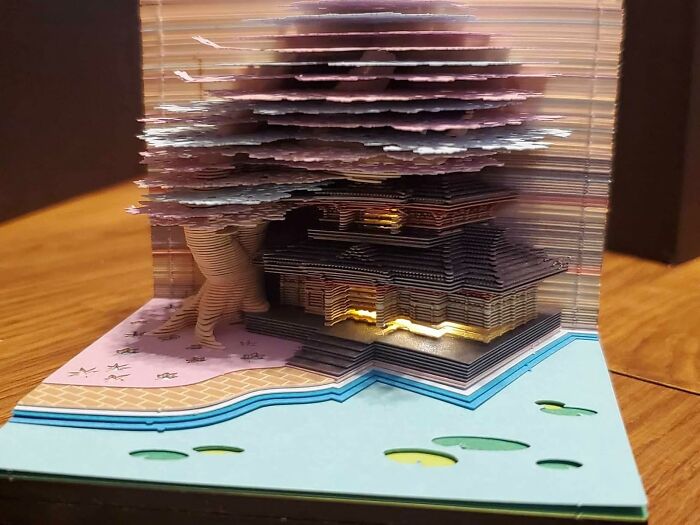 Intricate layered paper art depicting a house and tree by a pond, inspiring creative spirit with unique arty finds.