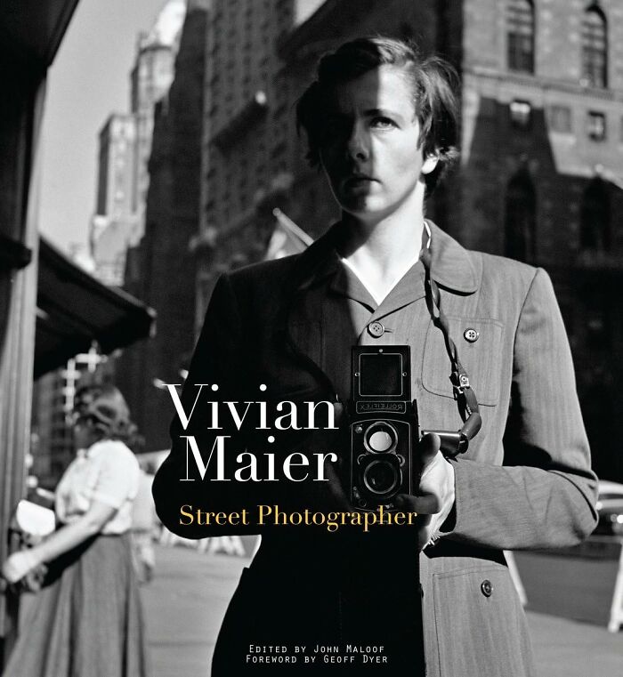 Black and white photo of Vivian Maier holding a vintage camera, highlighting influential legacies like Nikola Tesla.