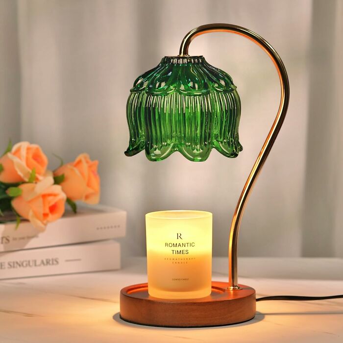 Green glass table lamp with wooden base and lit candle nearby, showcasing creative arty finds for home decor.