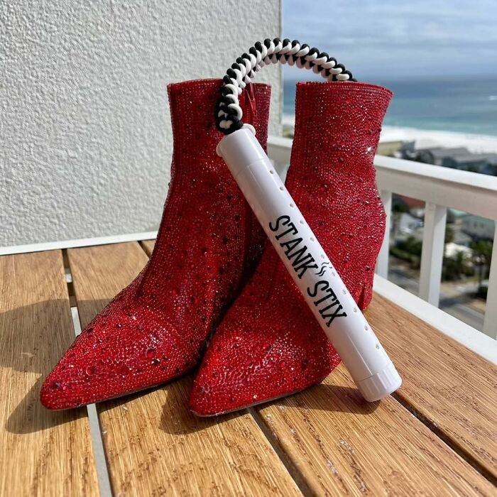 Red glittery boots on a wooden surface with a Stank Stix odor eliminator, unique product for specific problems.
