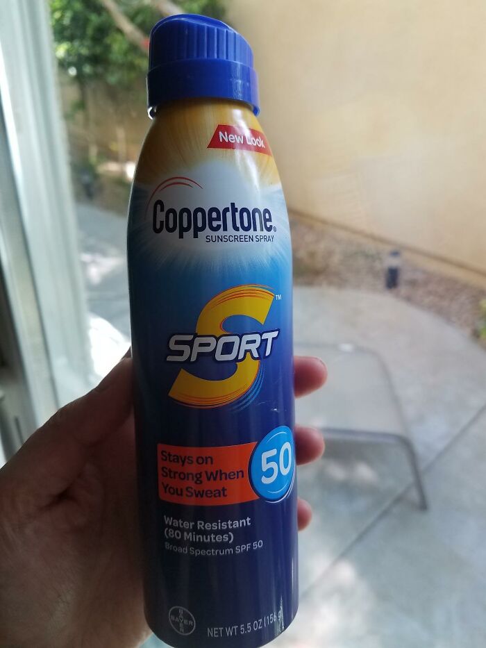 Hand holding a bottle of Coppertone sunscreen spray with SPF 50, highlighting solutions for fixing little glitches.