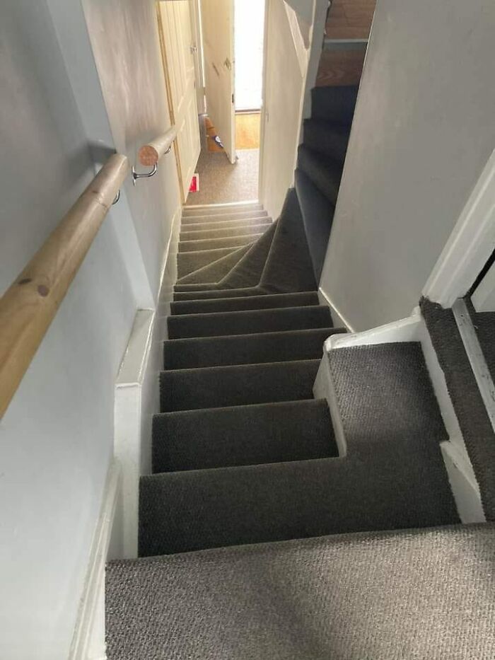 Steep narrow death stairs with sharp turn and carpeted steps in a small hallway, creating a risky walking path.