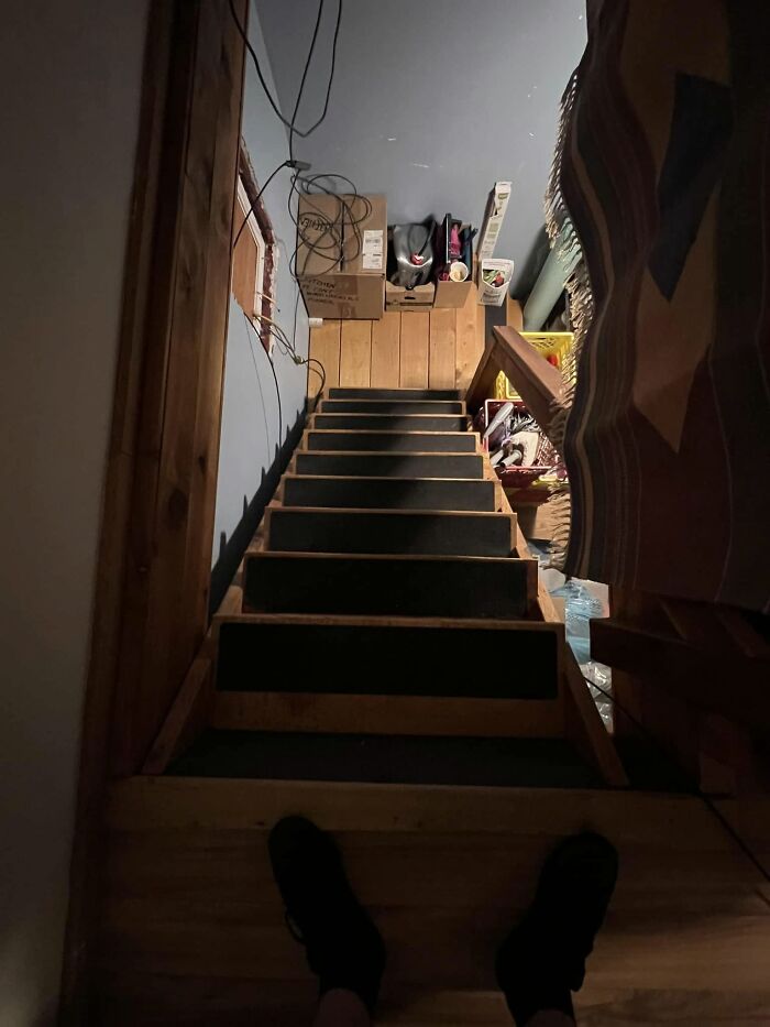 Steep and narrow death stairs leading down into a cluttered, dimly lit basement with uneven steps.