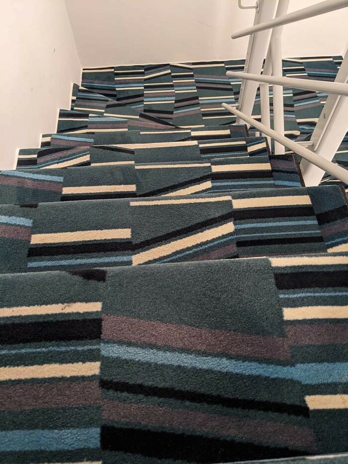 Stairs covered in a confusing patterned carpet that makes each step look uneven and dangerous to use.