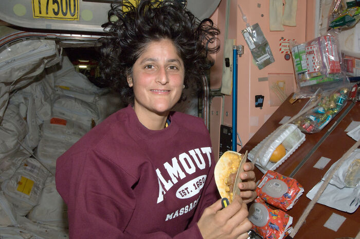 Astronaut with floating hair eating a taco inside a spacecraft, showcasing intriguing and bizarre astronaut facts.