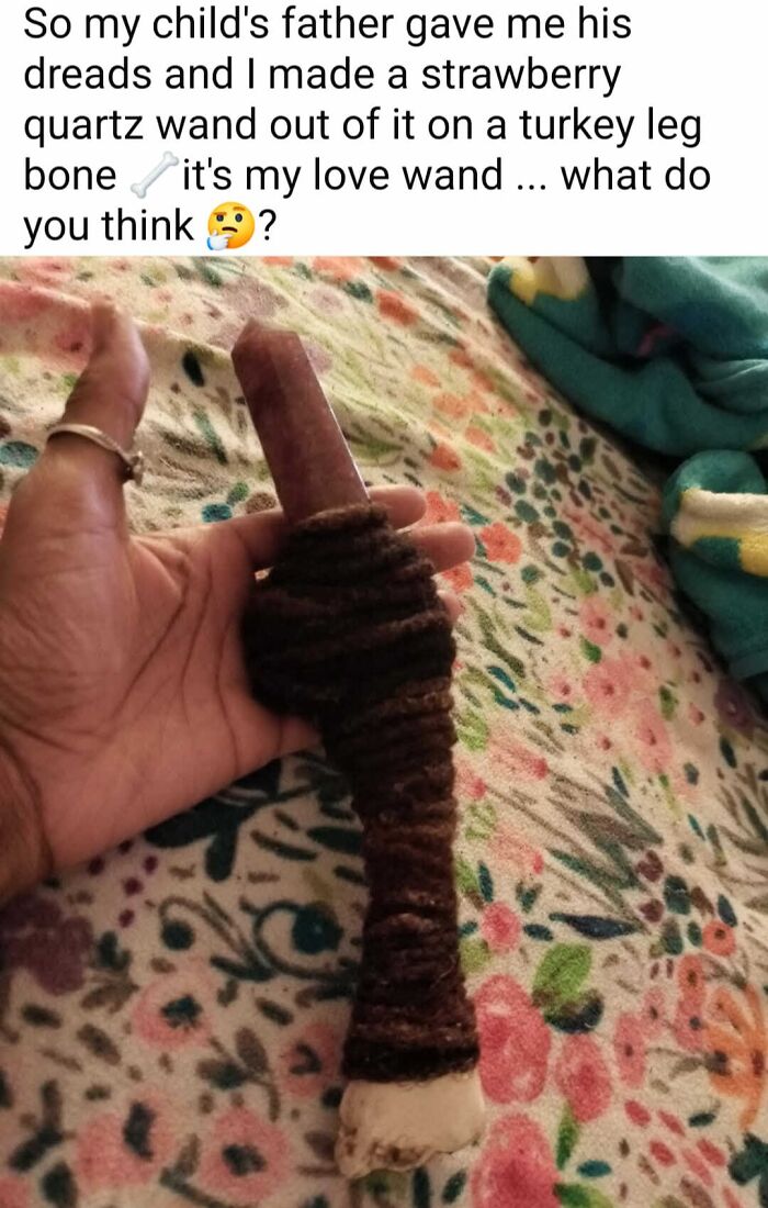 Hand holding a DIY strawberry quartz wand wrapped with dreadlocks on a turkey leg bone on a floral blanket.