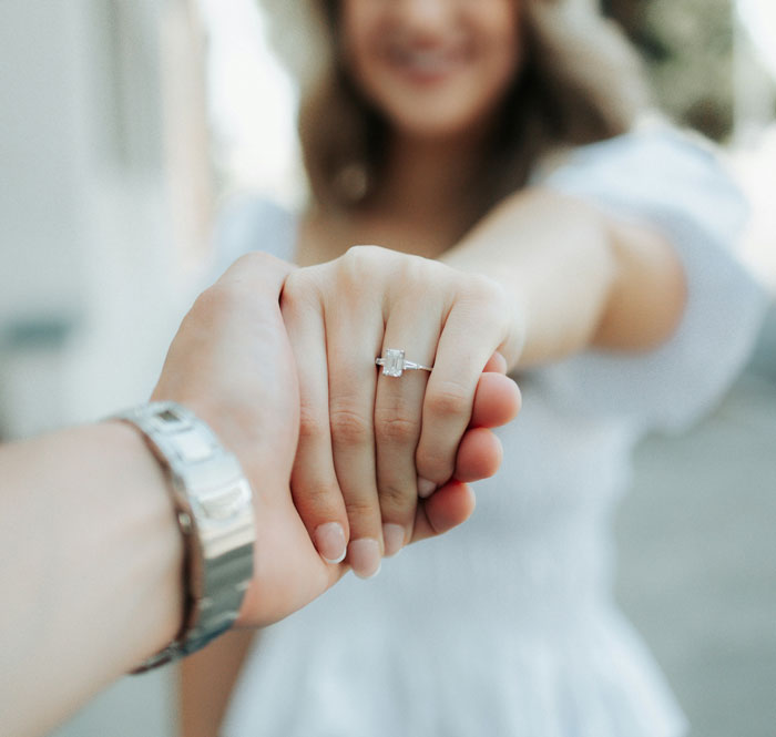 Bride holding hand showing engagement ring, representing a unique wedding where kids are replaced with pets.