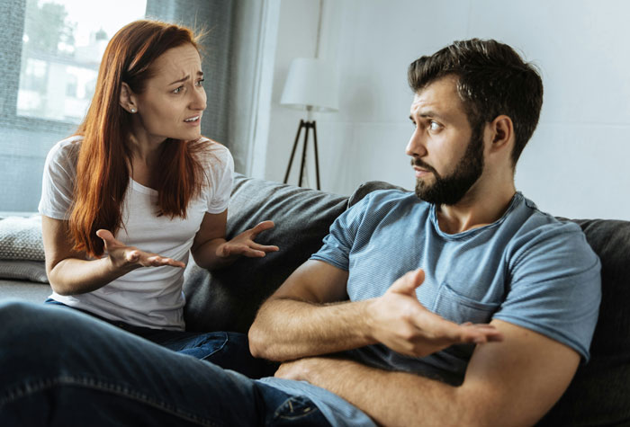 Young couple having a serious conversation on a couch, illustrating the biggest mistake of their lives concept.