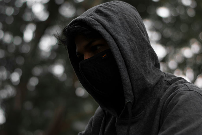 Person wearing a dark hoodie and face mask outdoors, symbolizing secrets about how I paid for college.
