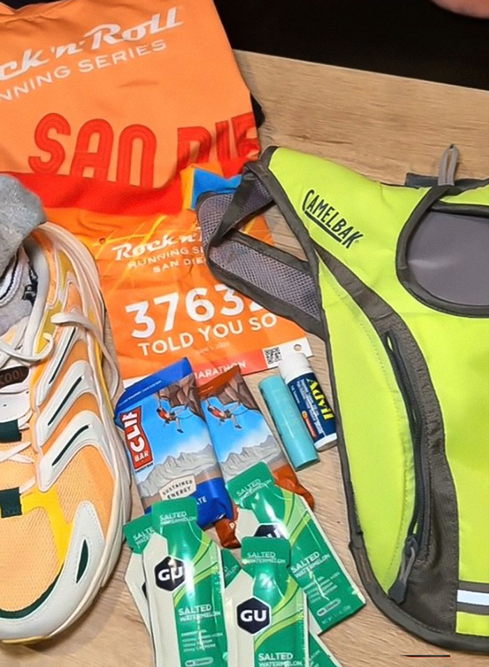 Running gear including shoes, energy gels, hydration pack, and marathon bib preparing for zero training marathon race.