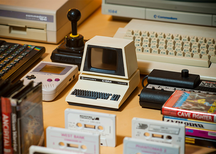 Collection of obsolete electronics and gaming devices including vintage computer, Game Boy, cassette tapes, and joystick still used daily.
