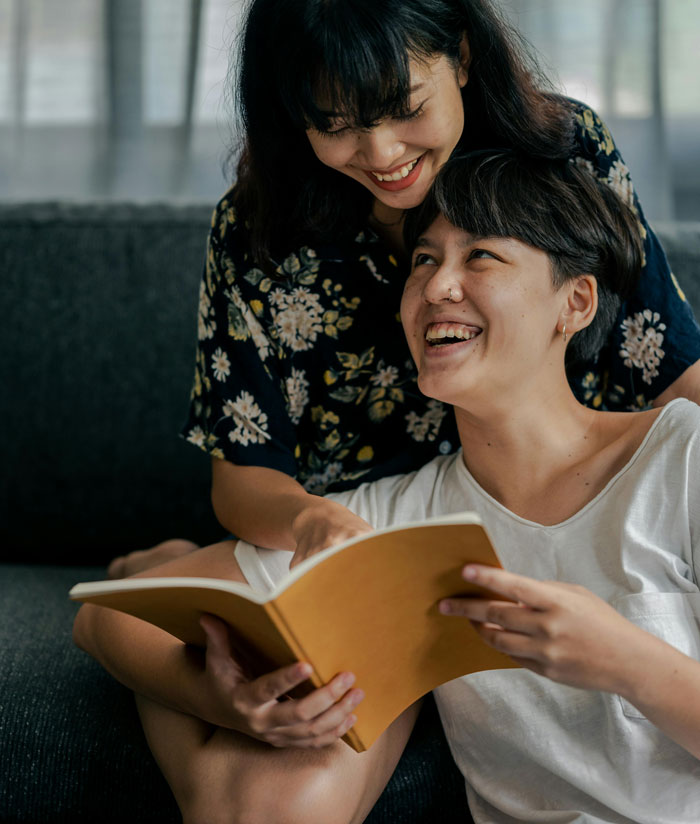 Two people sharing a joyful moment while reading a book, capturing the essence of therapy revelations and connection.