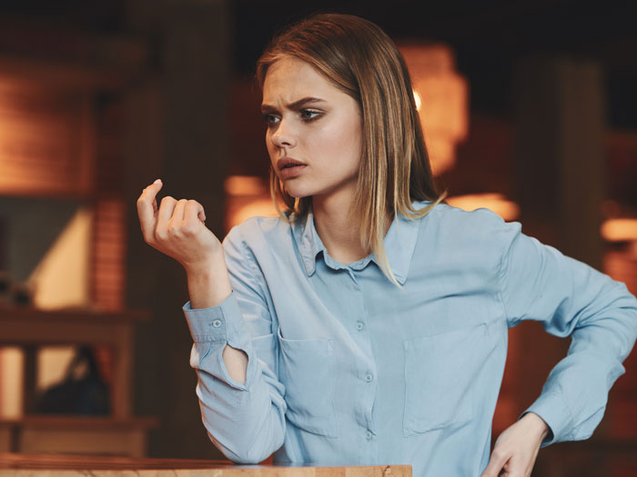 Woman in a blue shirt looking frustrated while thinking about babysitting kids on a colleague's day off at home. Woman in a blue shirt looking frustrated while thinking about babysitting kids on a colleague's day off at home.