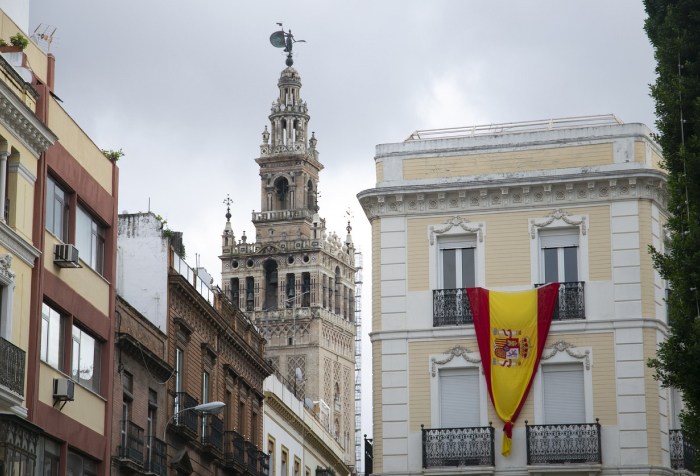 Street view of historic buildings in Spain with a Spanish flag, illustrating best countries to live in 2025 rankings.
