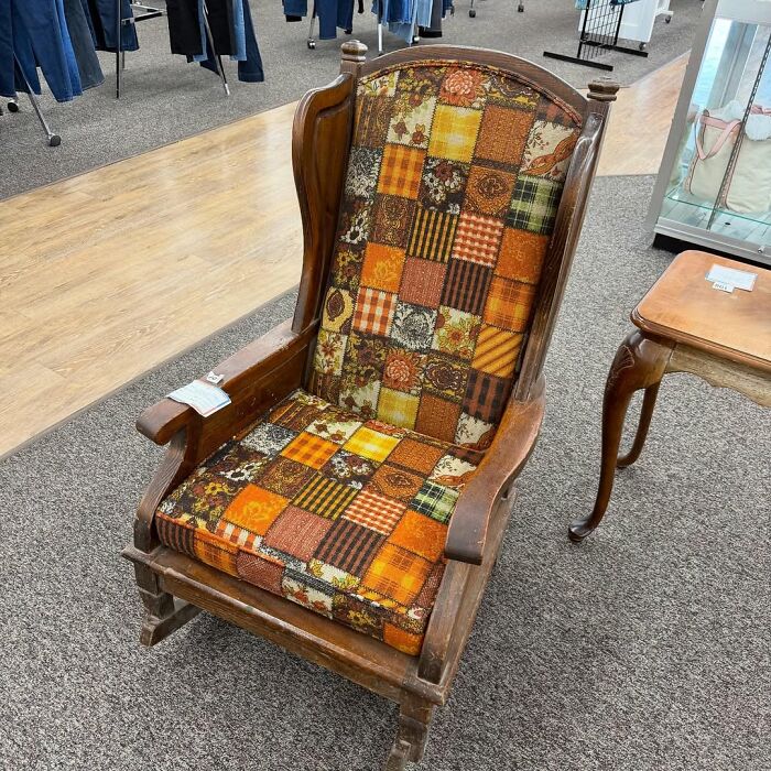 Vintage wooden rocking chair with colorful patchwork upholstery, a cool secondhand find in a thrift store setting.
