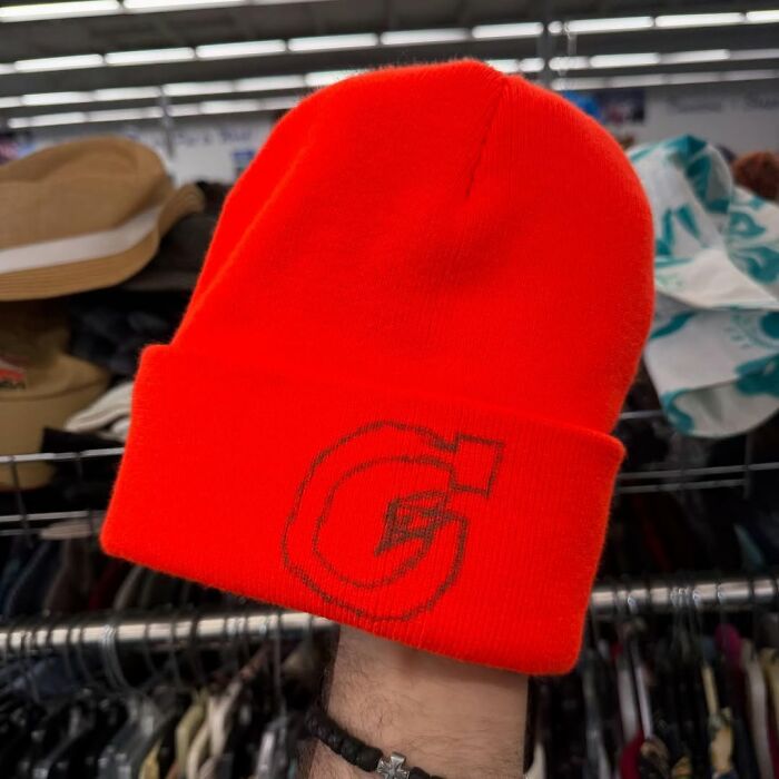 Bright orange beanie with a stylish logo, featured as a cool secondhand find in a thrift store setting.