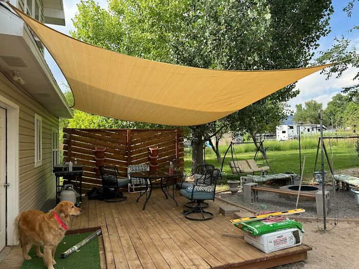 Backyard setup with shade sail, seating area, swing, and grill, perfect for summer Fourth of July parties.
