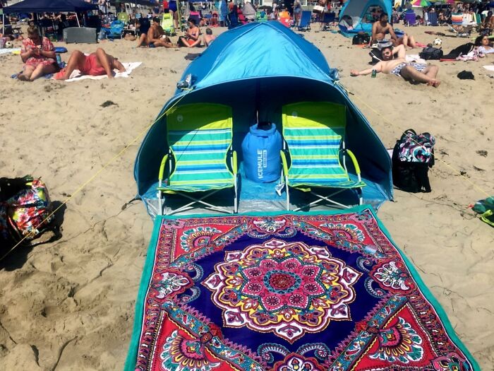Beach setup with shade tent, striped chairs, and colorful rug on sand, perfect for sun, sand, and snack attacks.
