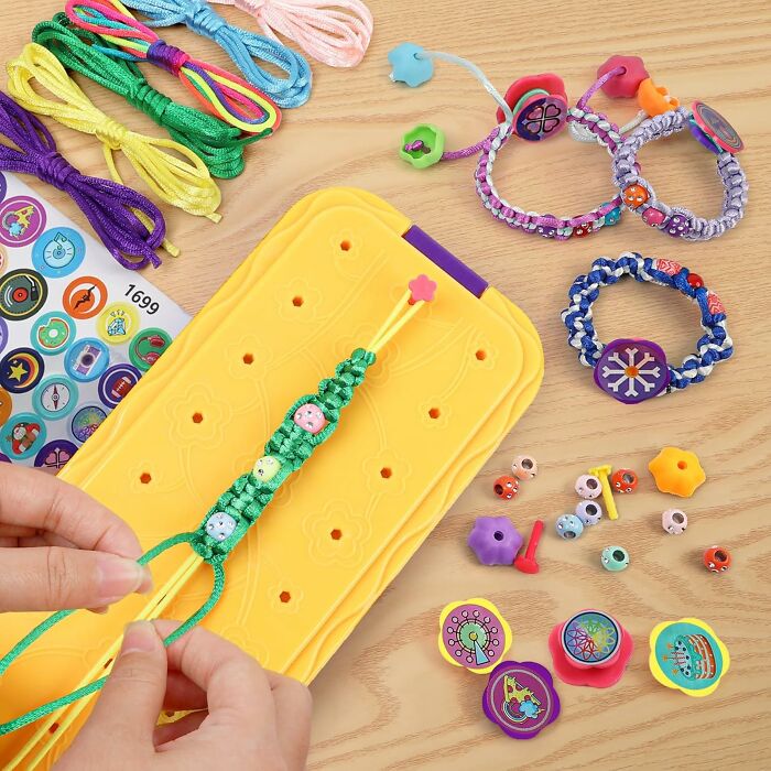 Hands creating a colorful macrame bracelet with beads and cords on a yellow board showcasing creative arty finds.
