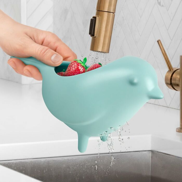 Blue bird-shaped strainer washing fresh strawberries under kitchen faucet, a genius kitchen find for Prime Day wishlist.