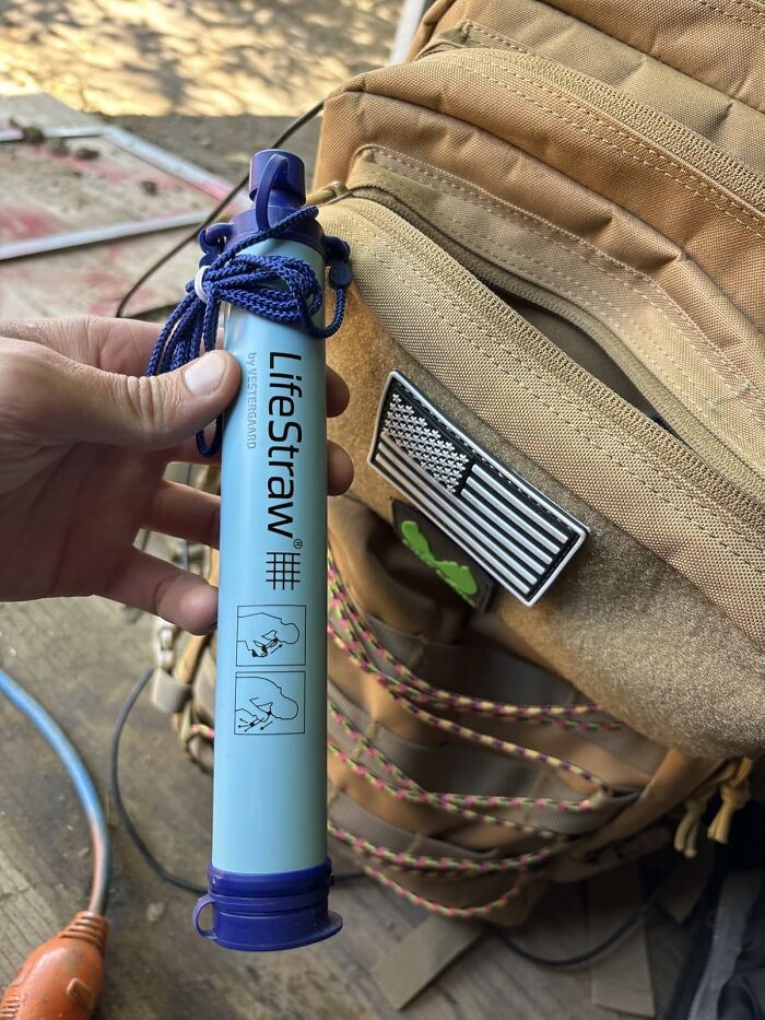 Hand holding a LifeStraw water filter with a tactical backpack in the background showcasing Prime Day deals under $25.