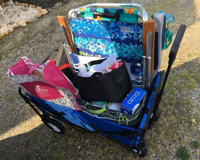 Foldable beach wagon packed with chairs, cooler, and bags ready for a day of sun, sand, and snack attacks.