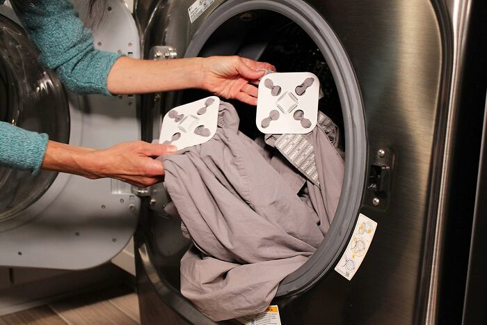 Person loading laundry into front load washing machine with laundry detergent strips, adulting starter pack essentials concept
