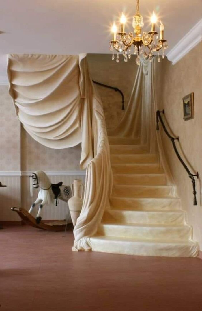 A death stairs design with fabric-like draped steps and a chandelier above in a vintage room.