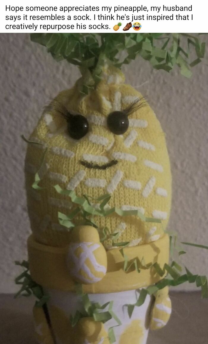 DIY craft project of a pineapple made from socks with painted details and fake eyelashes in a yellow pot.
