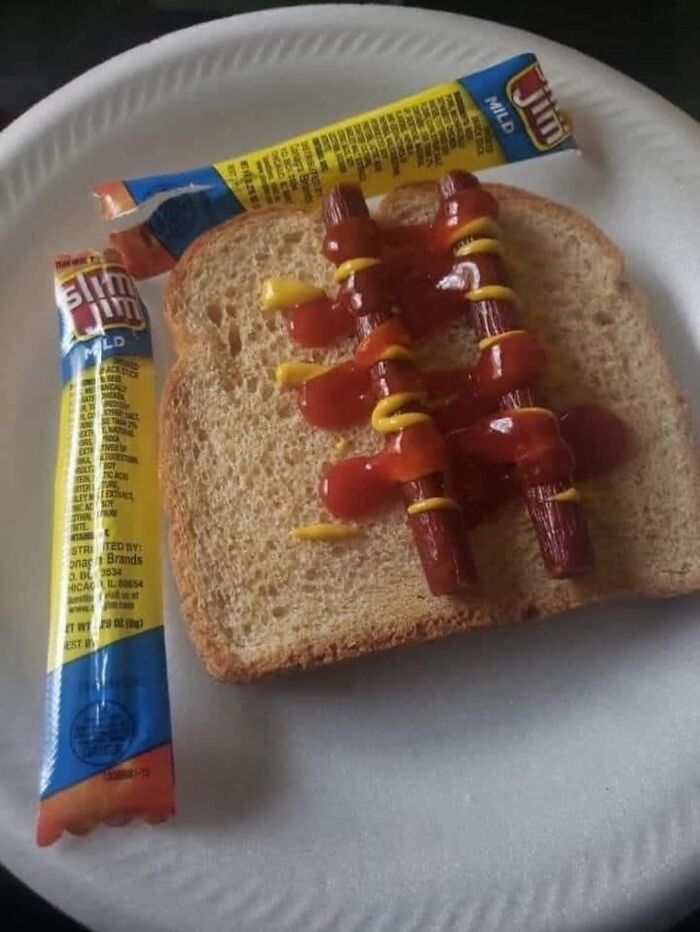 Two Slim Jim sticks on a slice of bread topped with mustard and ketchup, displayed on a paper plate.