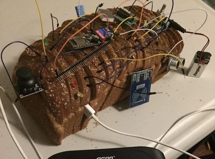 Sliced loaf of bread with electronic components and wires attached, creating a bizarre cursed food picture.